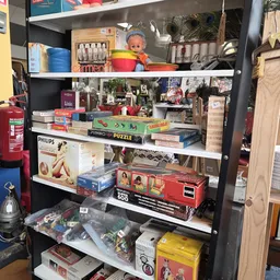 Stellingen met diverse tweedehands artikelen: puzzels, boeken, huishoudartikelen en speelgoed