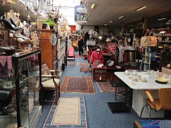 Winkelvloer van kringloopwinkel met diverse meubels, kleding, servies en huishoudelijke artikelen uitgestald