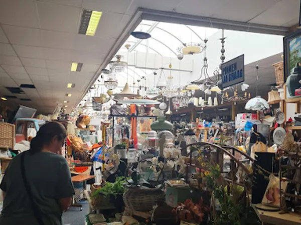 Overzicht van de winkelhal met stellingen vol spullen, hangende lampen en bezoekers die rondkijken