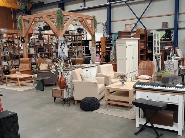 Winkelvloer met meubelstukken, zithoeken, houten pergola, boekenkast en diverse huisraad op uitgestalde locaties