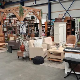 Winkelvloer met meubelstukken, zithoeken, houten pergola, boekenkast en diverse huisraad op uitgestalde locaties