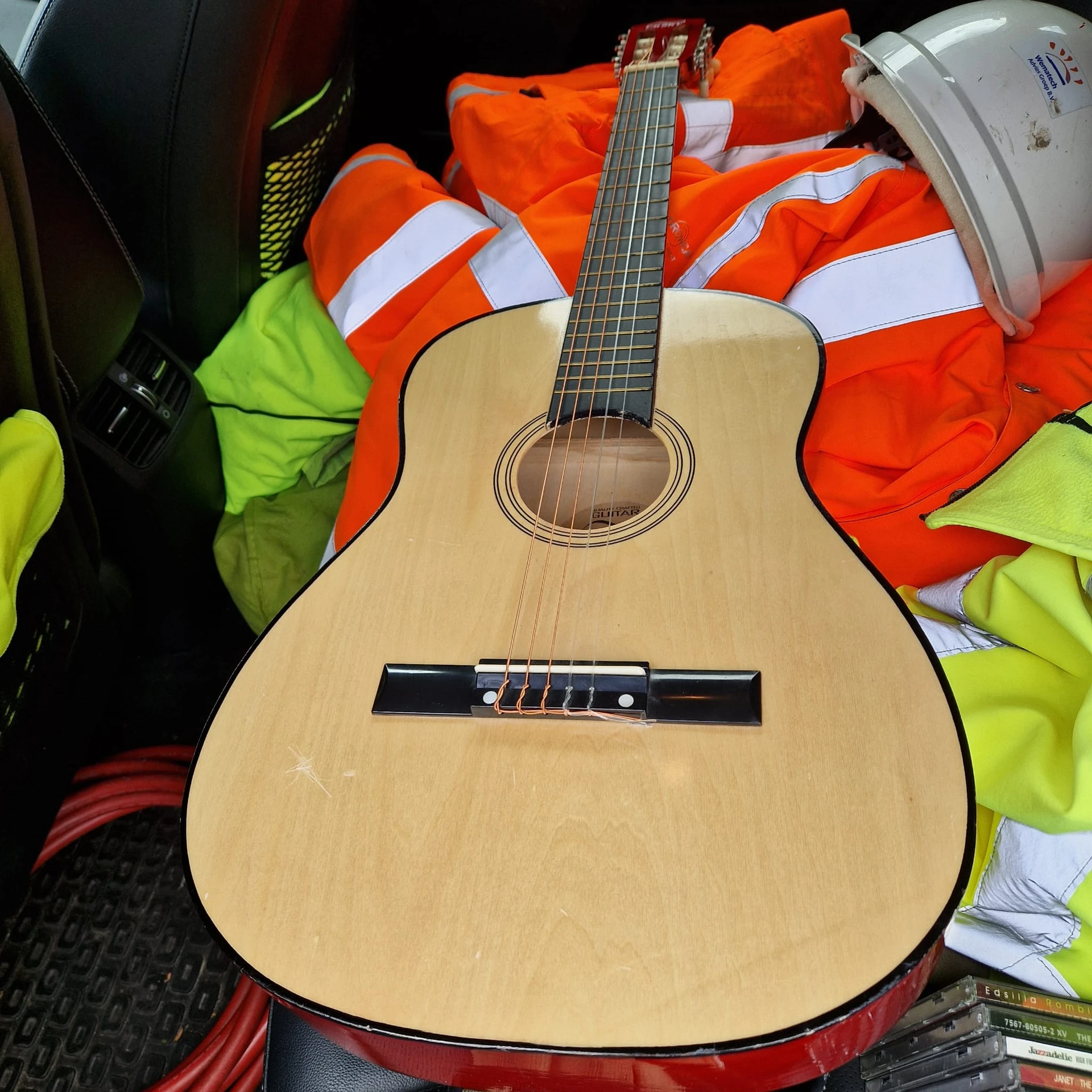 Close-up van een houten akoestische gitaar met nylon snaren op een achtergrond met oranje en groene kleding