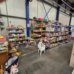 Winkelvloer met stellingen vol speelgoed, boeken en huishoudartikelen in een kringloopwinkel
