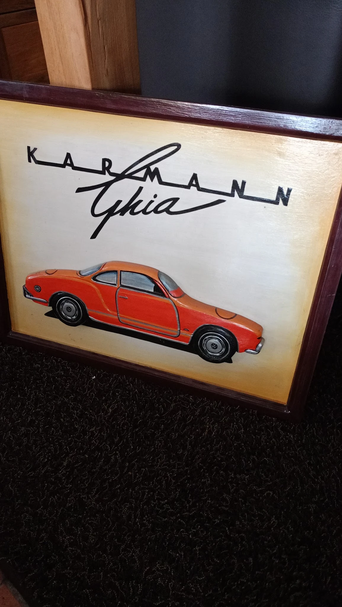 Rode speelgoedauto met openstaande deur tegen een muur met handtekening
