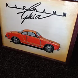 Rode speelgoedauto met openstaande deur tegen een muur met handtekening