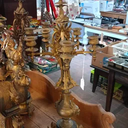 Gouden kandelaar met vier armen en ornamentale versiering op houten tafel