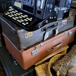 Gestapelde vintage koffers met op de bovenste een oude schrijfmachine met ronde toetsen