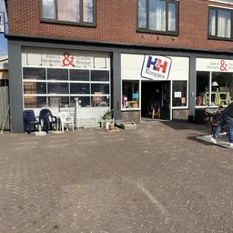 Gevel van kringloopwinkel met etalageruiten, ingang en uitstallingen op het terras