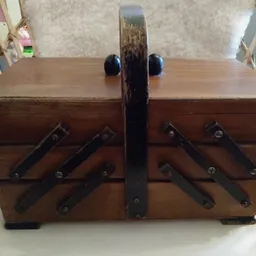 Houten naaisierbox met twee lagen, zwarte metalen hendels en donkerblauw handvat, gesloten.
