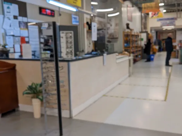 Binnenaanzicht van kringloopwinkel met balie, stellingen met spullen en klanten in het achtergrond