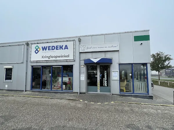 Witte gevel van kringloopwinkel Wedeka met blauwe accenten en winkelnaam duidelijk zichtbaar