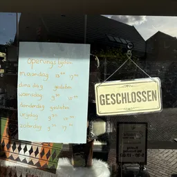 Handgeschreven openingstijden en gesloten-bord aan deur van winkel