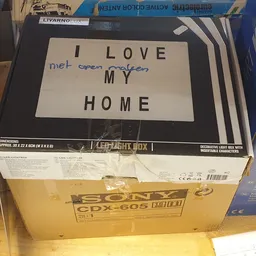 Lichtbak met tekst 'I LOVE MY HOME' op kartondoos in kringloopwinkel