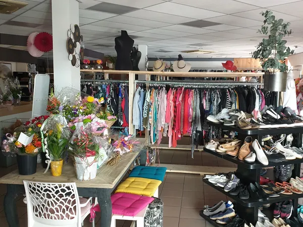 Winkelvloer met kledingrekken, schoenen, bloemen en poefjes in een kringloopwinkel