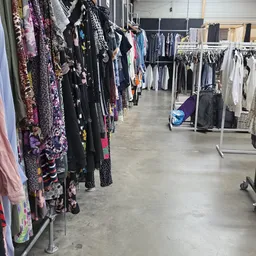 Rekken met tweedehands dameskleding in verschillende kleuren en patronen in de winkel