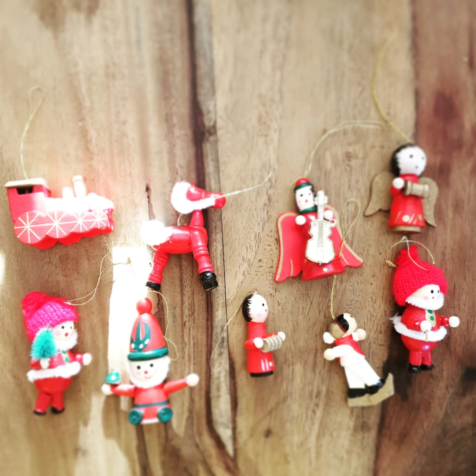 Verzameling houten kerstversieringen aan touwtjes, waaronder kerstmannen, sneeuwmannen en andere figuren in rood, wit en groe