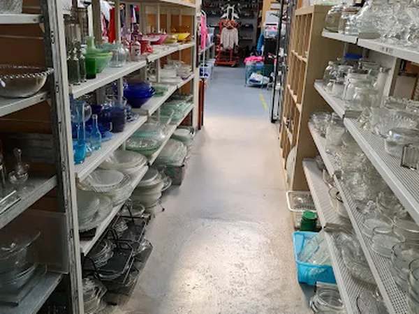 Winkelgang met stellingen vol glaswerk, servies en huishoudartikelen