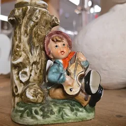 Vintage keramisch beeldje van een meisje met roze haar dat gitaar speelt, tegen decoratief achtergrond