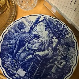 Decoratief bord met blauwe afbeelding van een historische tafereel met figuren