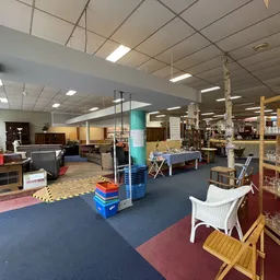 Winkelvloer van kringloopwinkel met stellingen, rekken met spullen, kleurrijke vloerbekleding en overhead verlichting