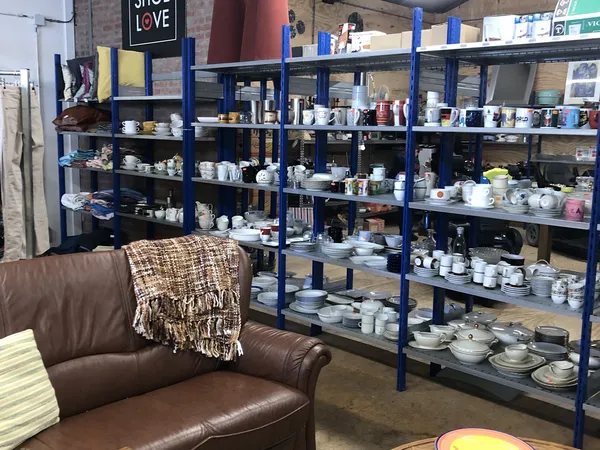 Winkelvloer met bruine leunstoel en blauwe stellingen vol met servies, vaatwerk en huishoudartikelen