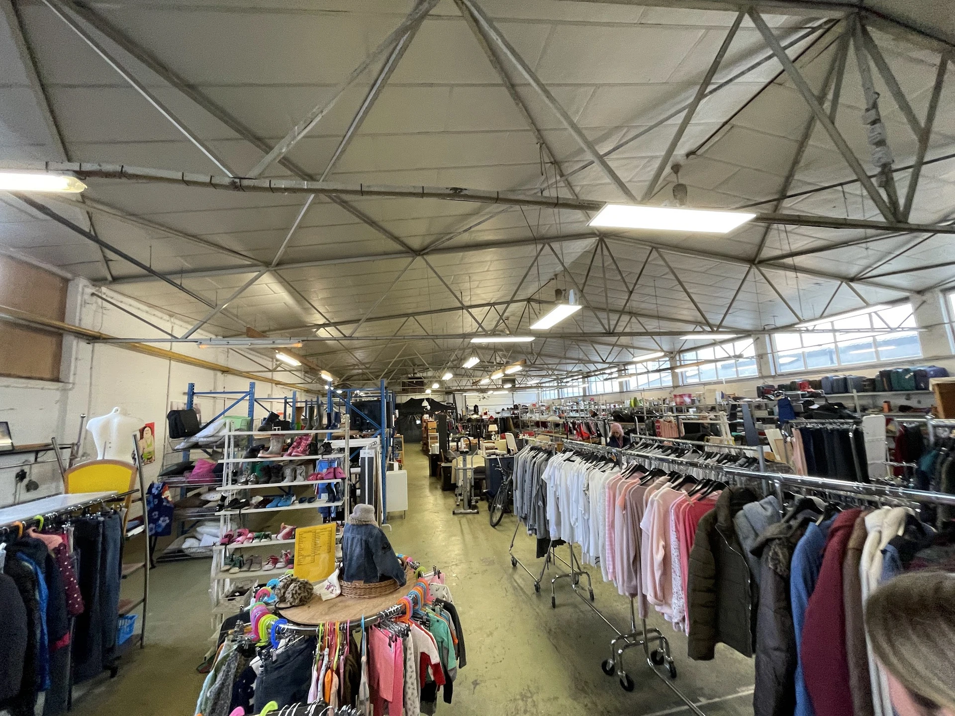 Overzicht van de winkelvloer met kledingrekken en stellingen vol tweedehands kleding