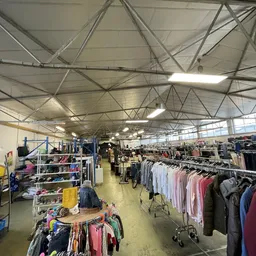 Overzicht van de winkelvloer met kledingrekken en stellingen vol tweedehands kleding