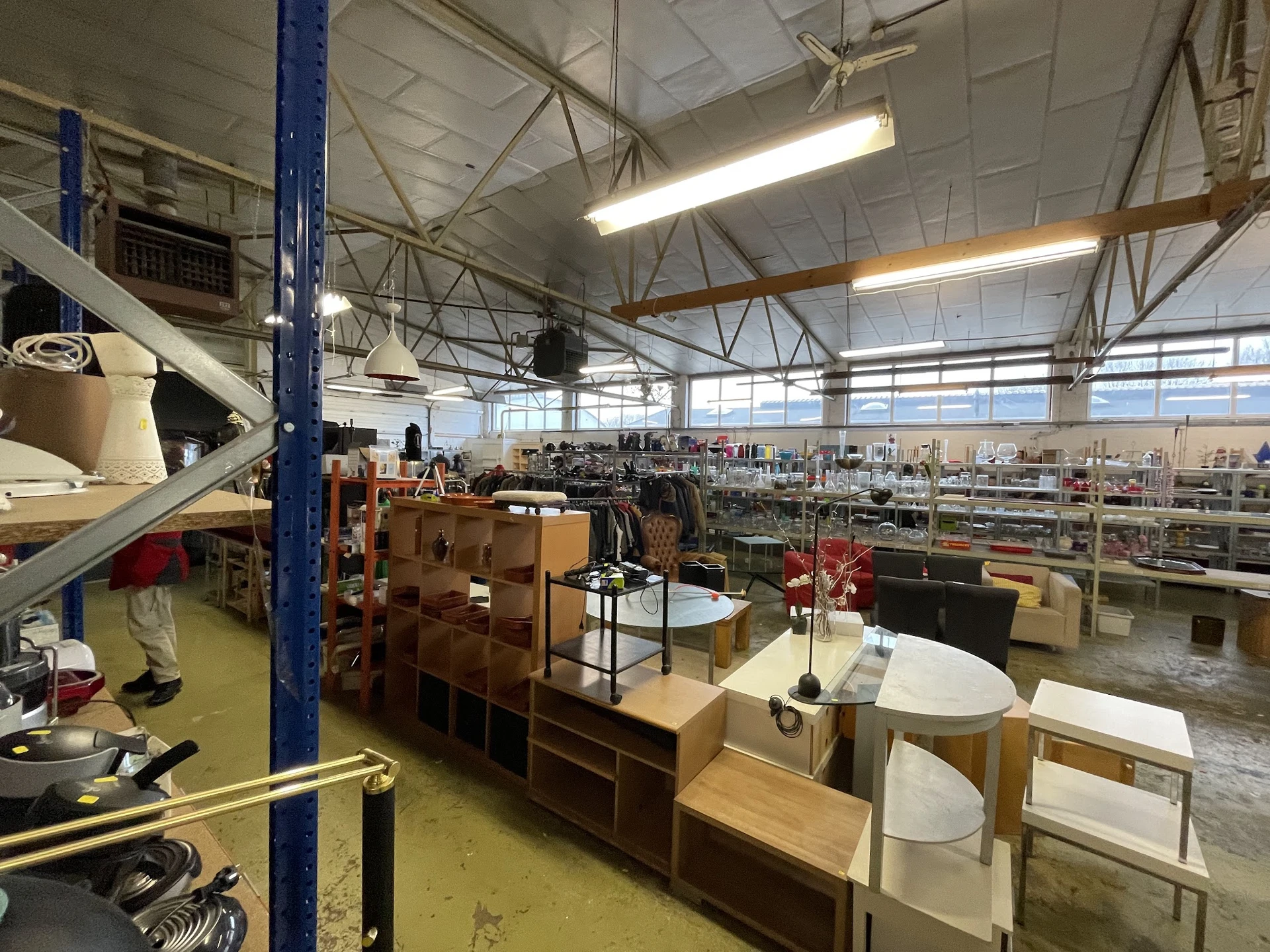 Overzicht van kringloopwinkel met meubels, huishoudartikelen en spullen op stellingen en display