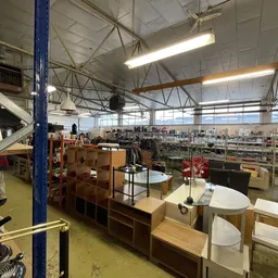 Overzicht van kringloopwinkel met meubels, huishoudartikelen en spullen op stellingen en display