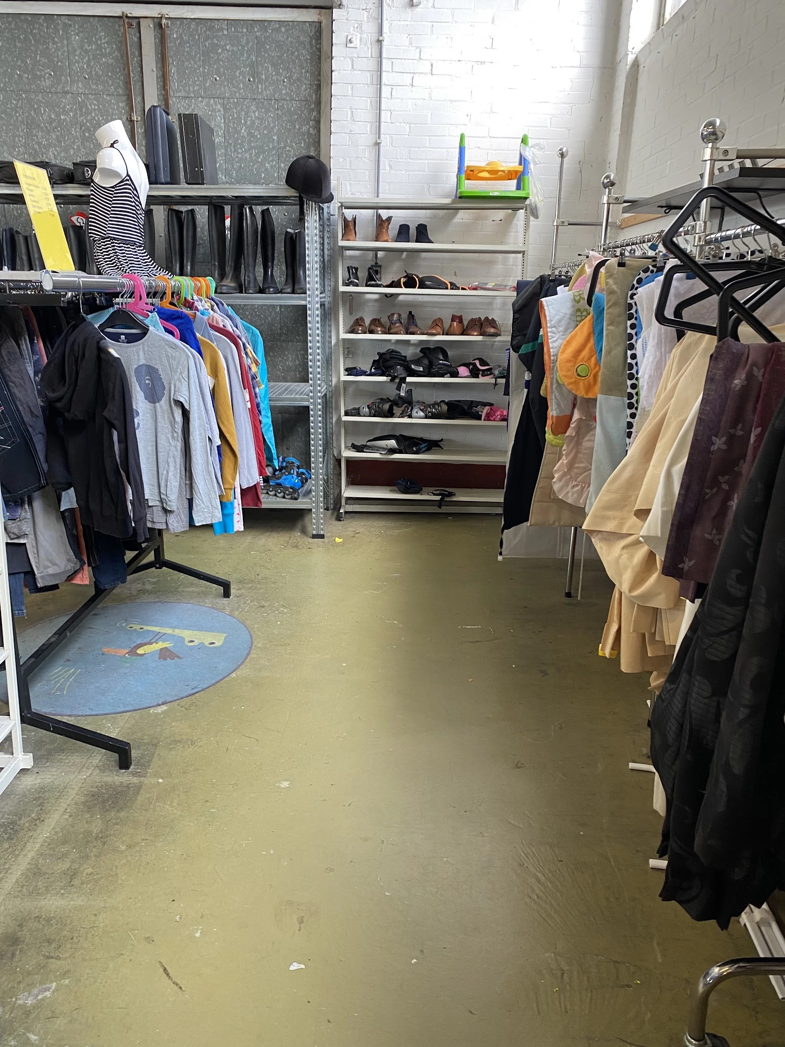 Winkelinterieur met kledingrekken en schoenenstellage, natte vloer na schoonmaak
