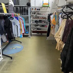 Winkelinterieur met kledingrekken en schoenenstellage, natte vloer na schoonmaak