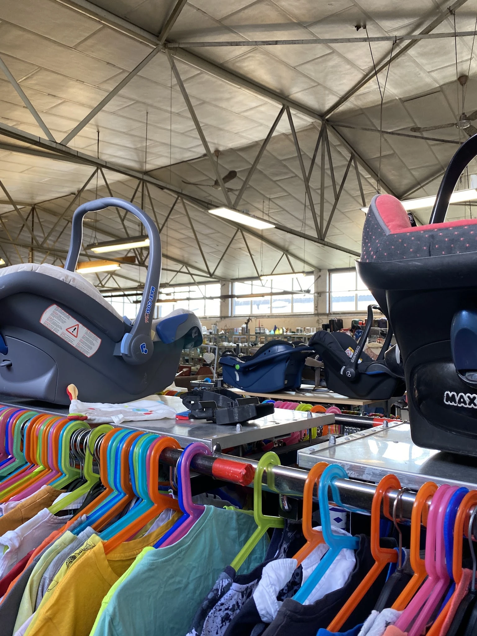 Verschillende tweedehands kinderstoelen, autostoeltjes en speelgoedartikelen uitgestald in de winkel