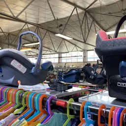 Verschillende tweedehands kinderstoelen, autostoeltjes en speelgoedartikelen uitgestald in de winkel