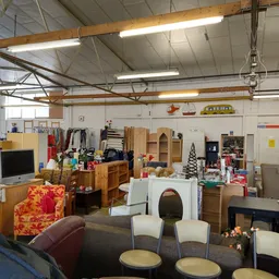Ruim magazijn met diverse tweedehands meubilair, kleding en huishoudspullen uitgestald