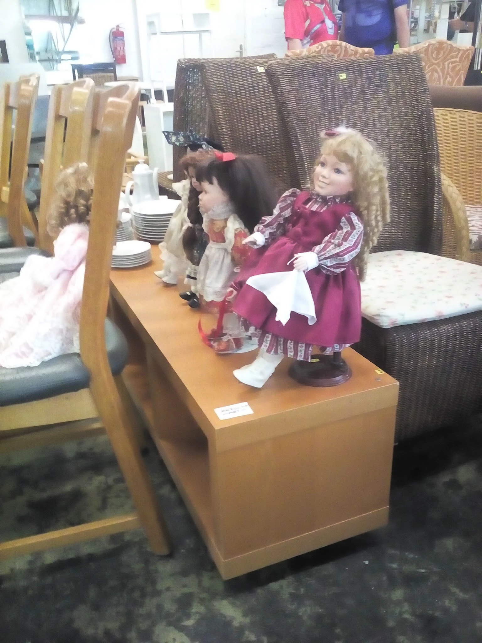 Verzameling porseleinen poppen in verschillende outfits en kleuren op een houten display