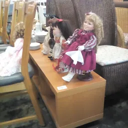 Verzameling porseleinen poppen in verschillende outfits en kleuren op een houten display