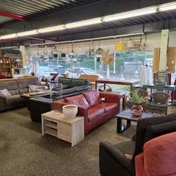 Winkelinterieur met meubels zoals banken en fauteuils in verschillende kleuren, tafels en stellingen met spullen