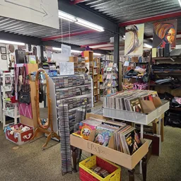 Winkelvloer van kringloopwinkel met rekken, kasten en dozen met tweedehands artikelen, kunstwerken aan de muren en verlichtin