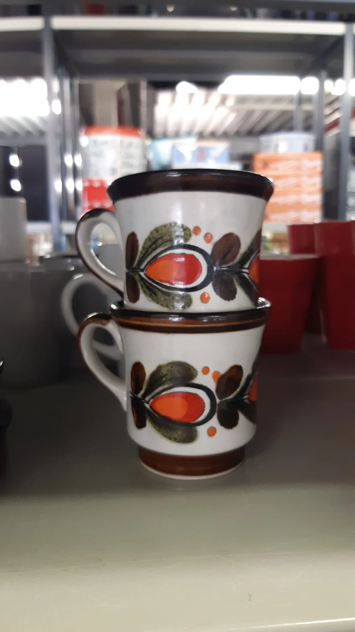 Twee gestapelde vintage koffiekopjes met oranje en bruine bloemendecoratie