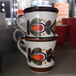 Twee gestapelde vintage koffiekopjes met oranje en bruine bloemendecoratie