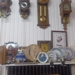 Uitgestalde decoratieve artikelen: wandklokken, borden, servies en andere vintage huishoudartikelen op een plank