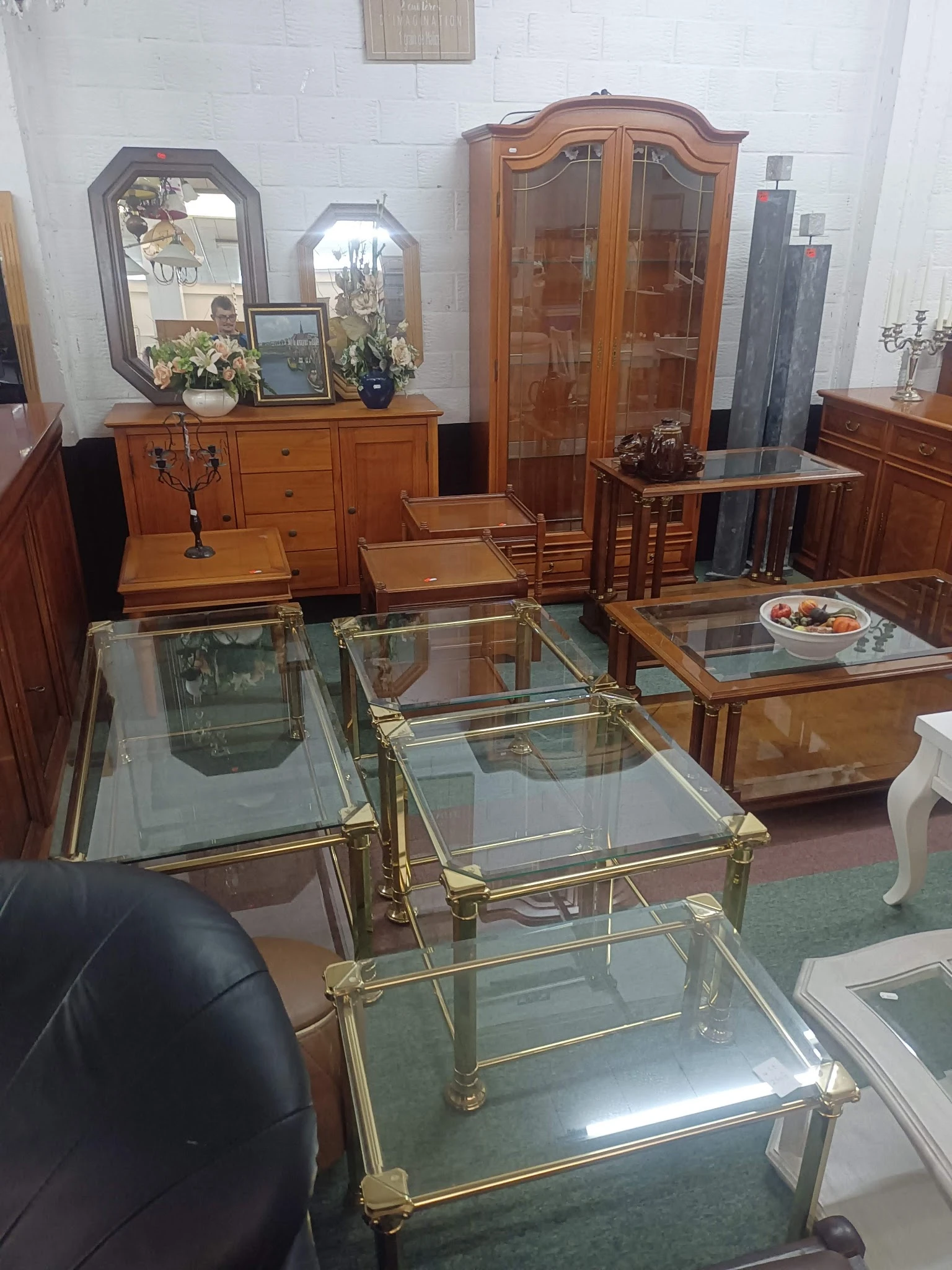 Glazen salontafels met messingframe en houten meubels in een kringloopwinkel