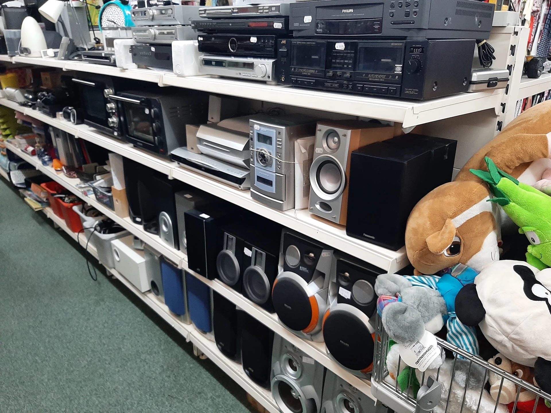 Schappen met tweedehands elektronische apparaten: versterkers, speakers, cd-spelers en ander audio-apparatuur