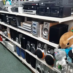 Schappen met tweedehands elektronische apparaten: versterkers, speakers, cd-spelers en ander audio-apparatuur