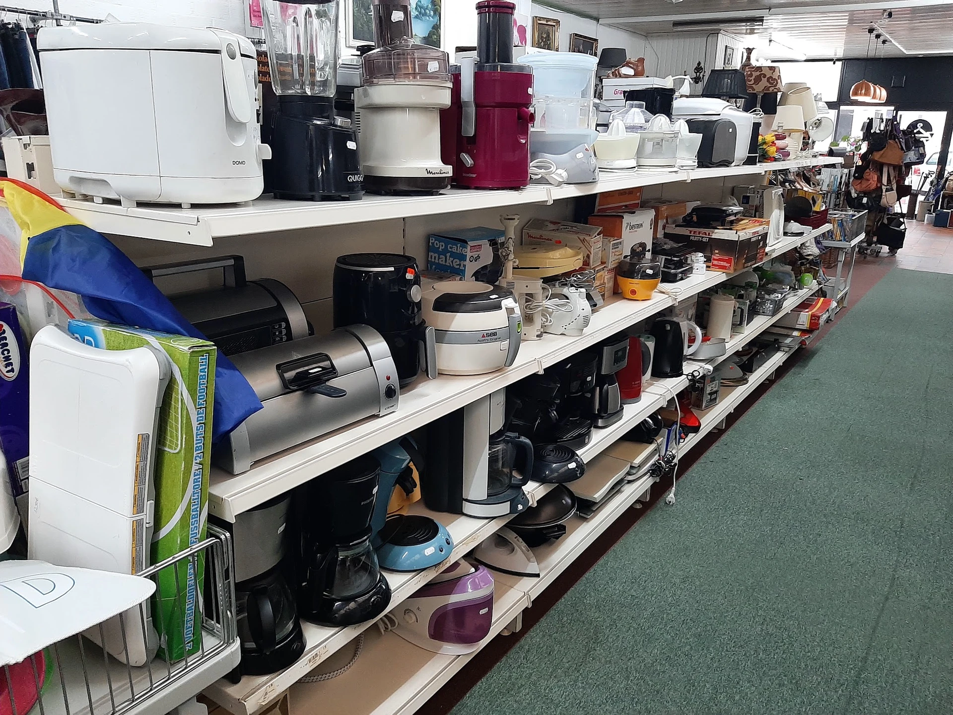 Lange stellingen volgestapeld met gebruikt keukengerei, elektrische apparaten en huishoudelijke items