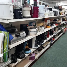 Lange stellingen volgestapeld met gebruikt keukengerei, elektrische apparaten en huishoudelijke items
