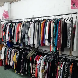 Rekken met tweedehands kleding in verschillende kleuren en stijlen