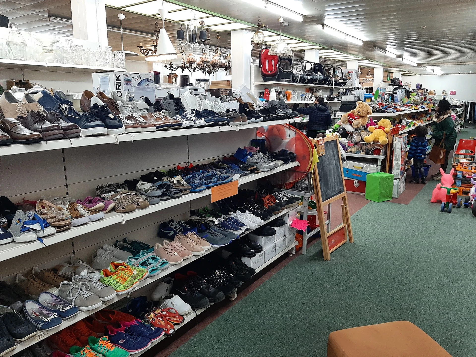 Overzicht van winkelvloer met rekken vol kleding, schoenen en diverse spullen