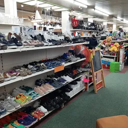 Overzicht van winkelvloer met rekken vol kleding, schoenen en diverse spullen