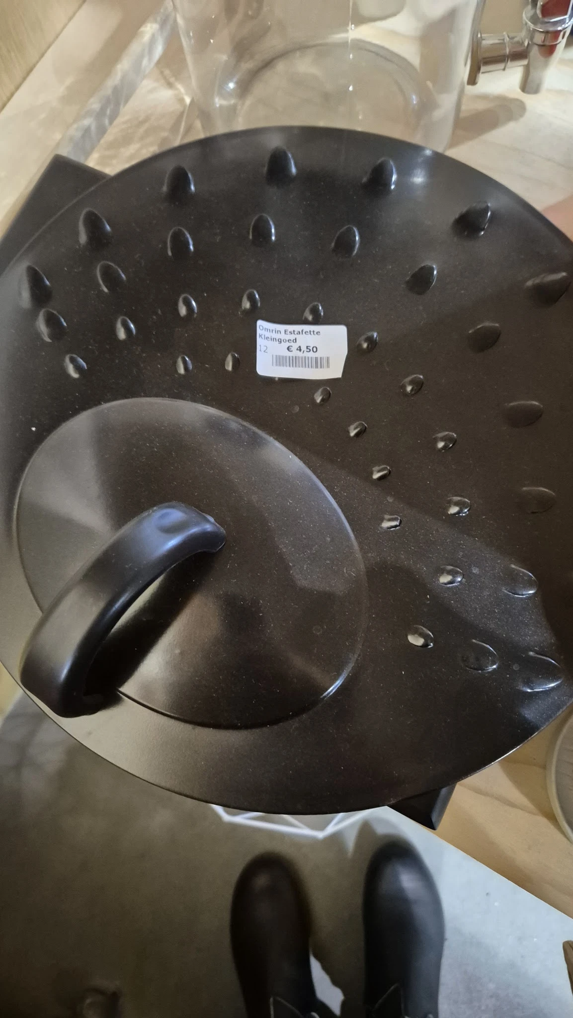 Grijze metalen saladeslinger met zwart handvat, op display met prijskaartje €4,50